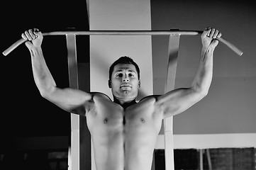 Image showing young man with strong arms working out in gym