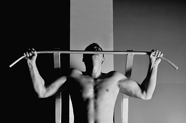 Image showing young man with strong arms working out in gym