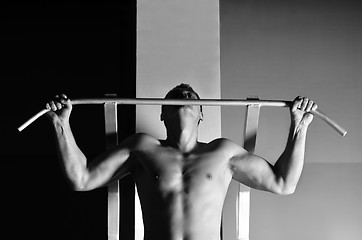 Image showing young man with strong arms working out in gym