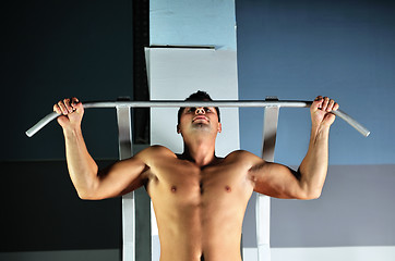 Image showing young man with strong arms working out in gym