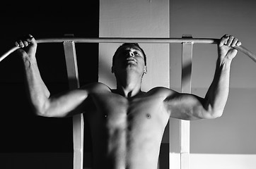 Image showing young man with strong arms working out in gym