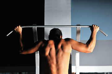 Image showing young man with strong arms working out in gym