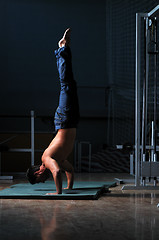 Image showing young man performing handstand in fitness studio