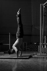 Image showing young man performing handstand in fitness studio