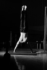 Image showing young man performing handstand in fitness studio