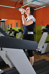 Image showing Young woman drinking water while working out