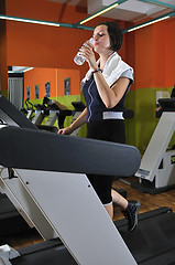 Image showing Young woman drinking water while working out