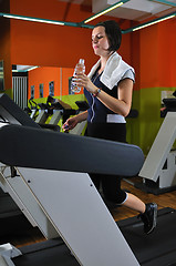 Image showing Young woman drinking water while working out