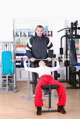 Image showing .man assisting woman weitght lifting at a gym 