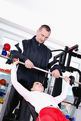 Image showing .man assisting woman weitght lifting at a gym 
