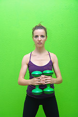Image showing Pretty girl with dumbbells and green backgound