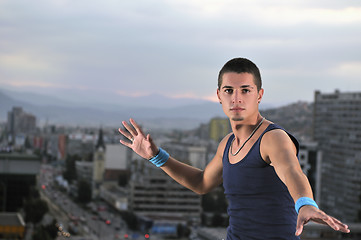 Image showing young man dancing and jumping  on top of the building 