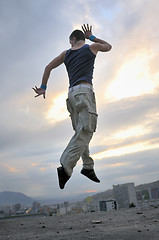 Image showing young man dancing and jumping  on top of the building 