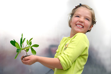 Image showing little girl holding small plant