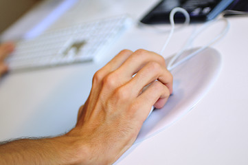 Image showing lose-up of male hand on mouse while working on laptop