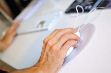 Image showing lose-up of male hand on mouse while working on laptop