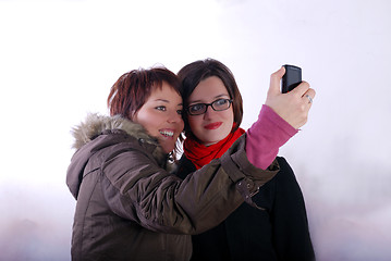 Image showing Tow ladies taking picture with mobile phone 