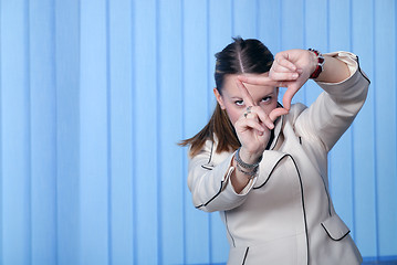 Image showing portrait of young business woman creates a frame with her hands