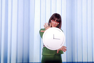 Image showing .a pretty business woman hiding behind a clock