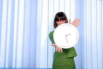 Image showing .a pretty business woman hiding behind a clock