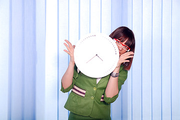 Image showing .a pretty business woman hiding behind a clock