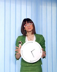 Image showing .a pretty business woman hiding behind a clock