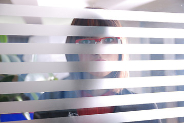 Image showing young businesswoman looking trought transparent wall