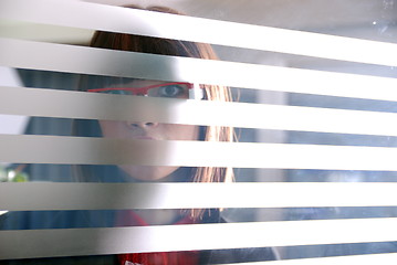 Image showing young businesswoman looking trought transparent wall