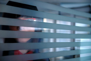 Image showing young businesswoman looking trought transparent wall