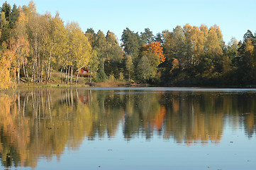 Image showing Cabin by lake in autumn colors