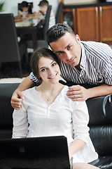 Image showing joyful couple relax and work on laptop computer at modern home