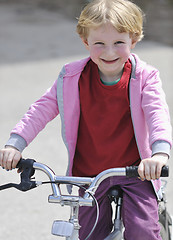 Image showing cute little girl driving bicyle at sunny day