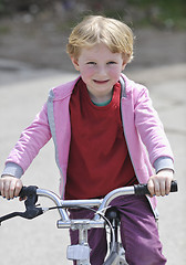 Image showing cute little girl driving bicyle at sunny day