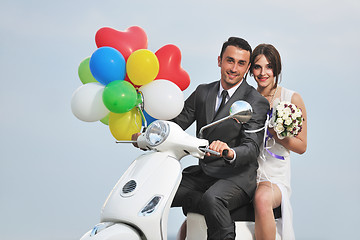 Image showing just married couple on the beach ride white scooter