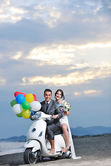 Image showing just married couple on the beach ride white scooter