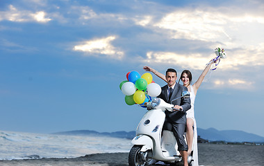 Image showing just married couple on the beach ride white scooter