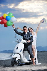 Image showing just married couple on the beach ride white scooter