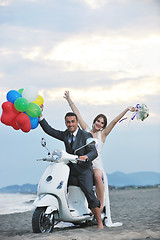 Image showing just married couple on the beach ride white scooter