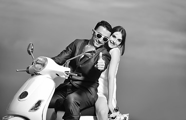 Image showing just married couple on the beach ride white scooter