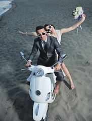 Image showing just married couple on the beach ride white scooter