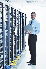 Image showing businessman with laptop in network server room