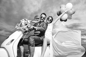 Image showing just married couple on the beach ride white scooter