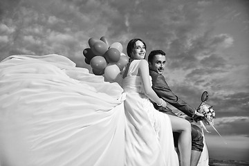 Image showing just married couple on the beach ride white scooter