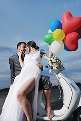 Image showing just married couple on the beach ride white scooter