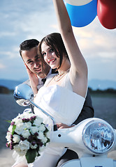 Image showing just married couple on the beach ride white scooter