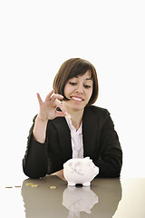 Image showing business woman putting coins money in piggy bank