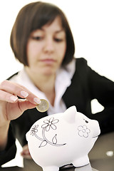 Image showing business woman putting coins money in piggy bank