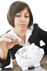 Image showing business woman putting coins money in piggy bank