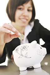 Image showing business woman putting coins money in piggy bank