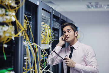 Image showing it engeneer talking by phone at network room